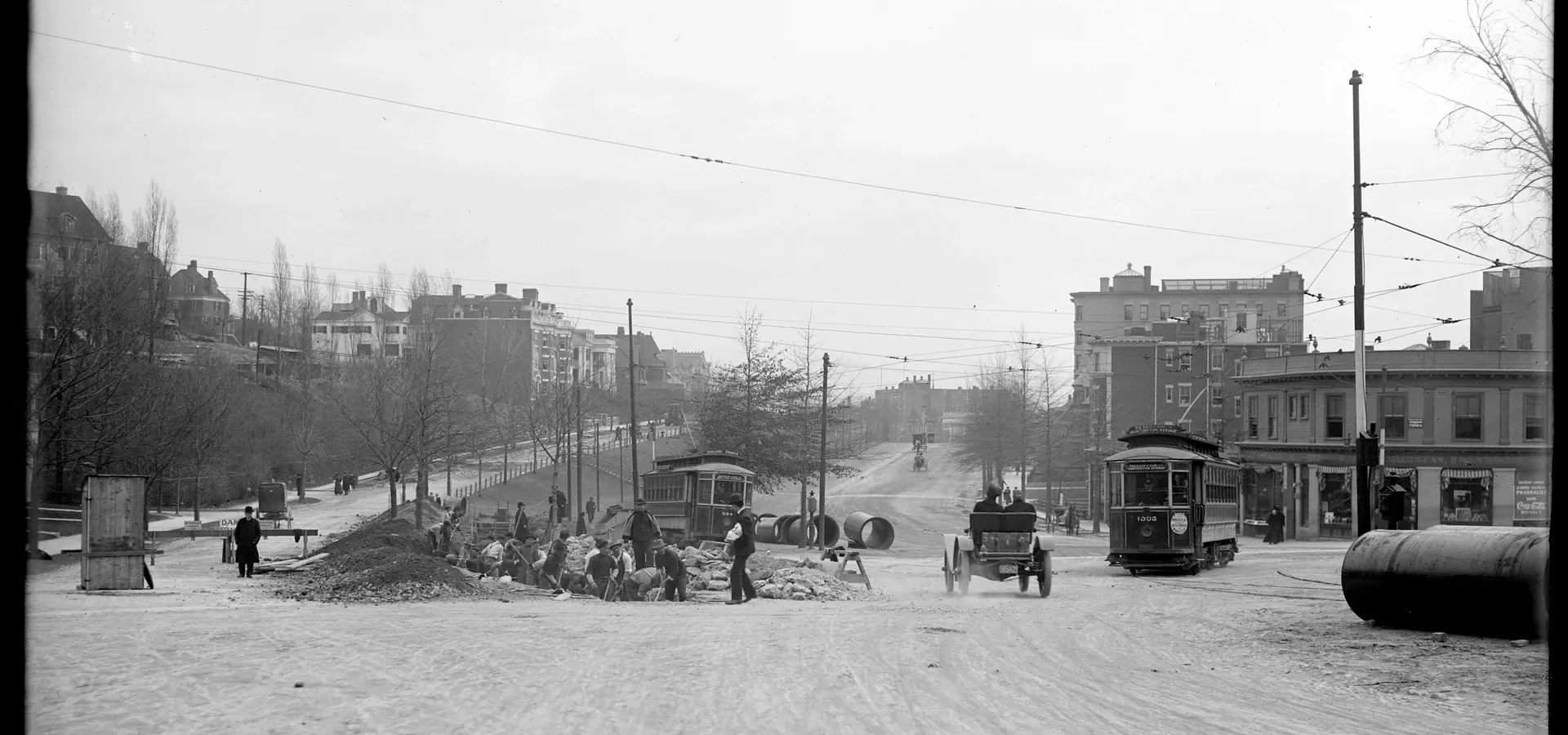 Historic black-and-white photo of workers digging in a city street with streetcars