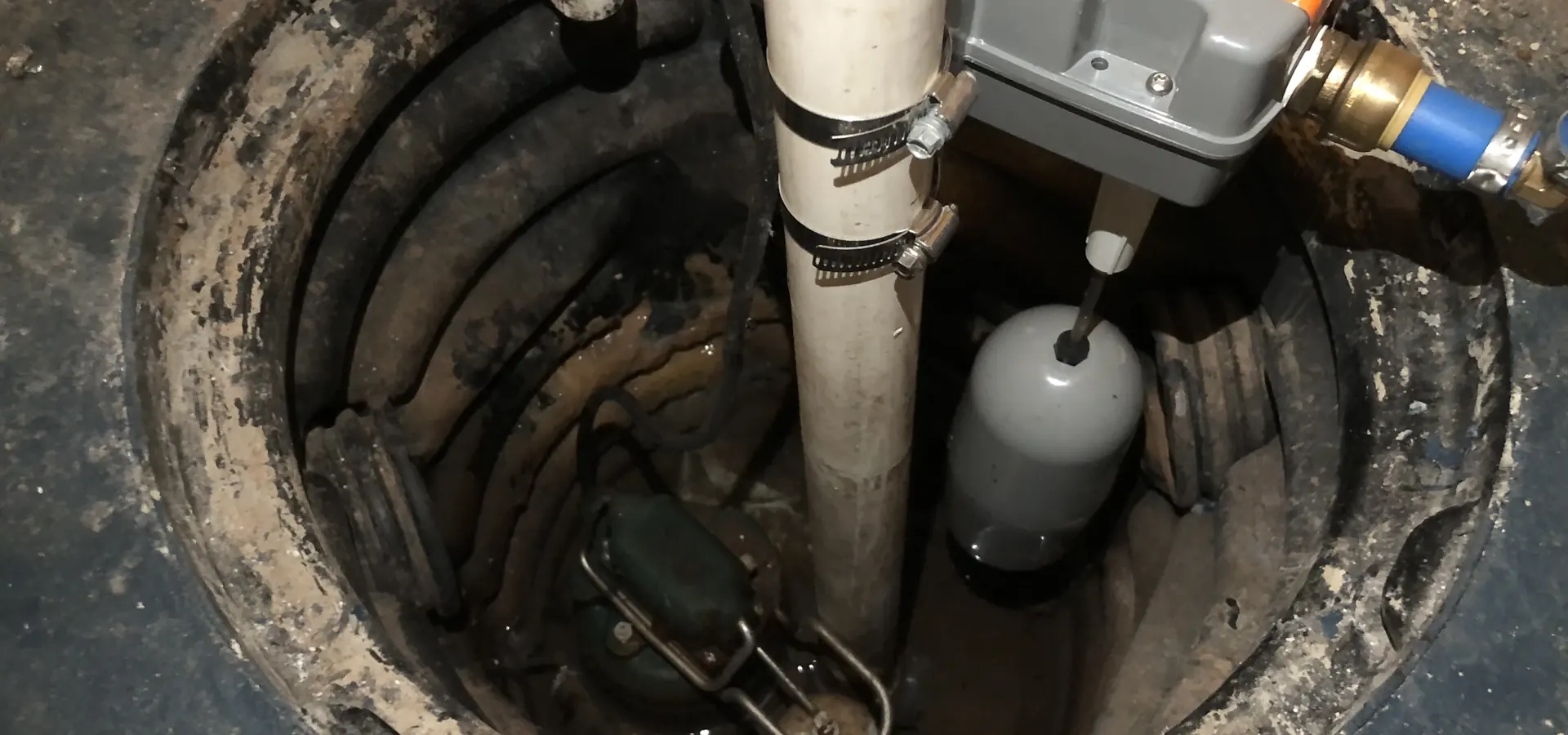 Looking down into a sump pit at a pump and discharge pipe